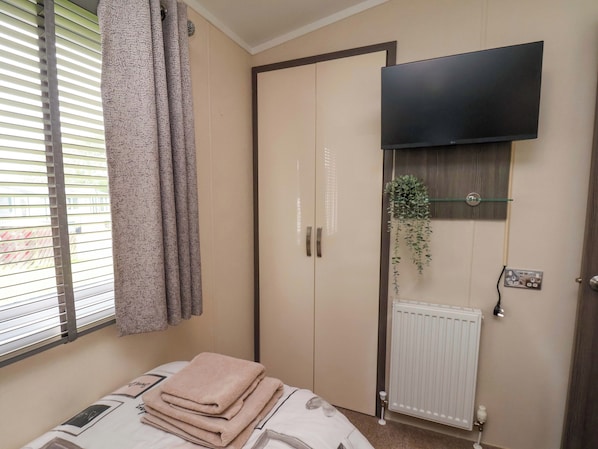 A bedroom with a bed, a wardrobe, a radiator, a TV, and a window with blinds. - Finch 66 (Scarborough)