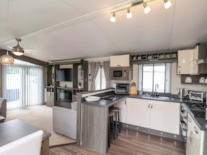 A modern kitchen with a built-in microwave, oven, and toaster, a dining area with a table and chairs, and a large window providing natural light. - Finch 66 (Scarborough)
