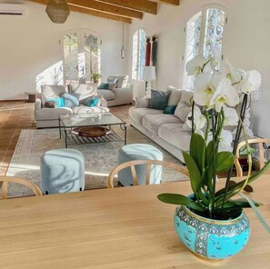 Ein modernes Wohnzimmer mit einer Couch, Sesseln, einem Couchtisch und einer dekorativen Vase mit Blumen.