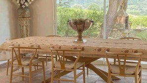 A dining area with a large table, chairs, and a vase of flowers. - Estate with olive grove near Grimaud (Cogolin)