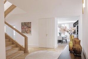 Ein modernes Interieur mit einer Holztreppe, einer weißen Tür und einem Essbereich mit Tisch und Stühlen.