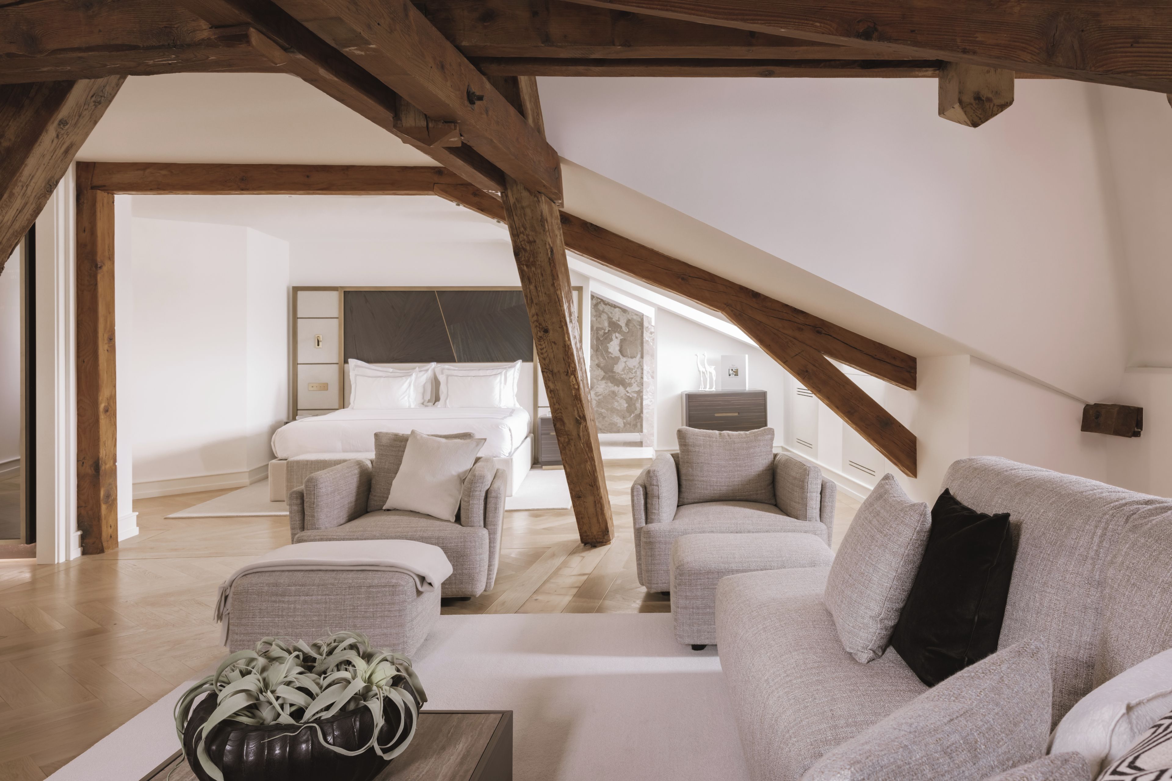 Een slaapkamer in een loft met een schuine kap, een bed, een slaapbank en een salontafel.