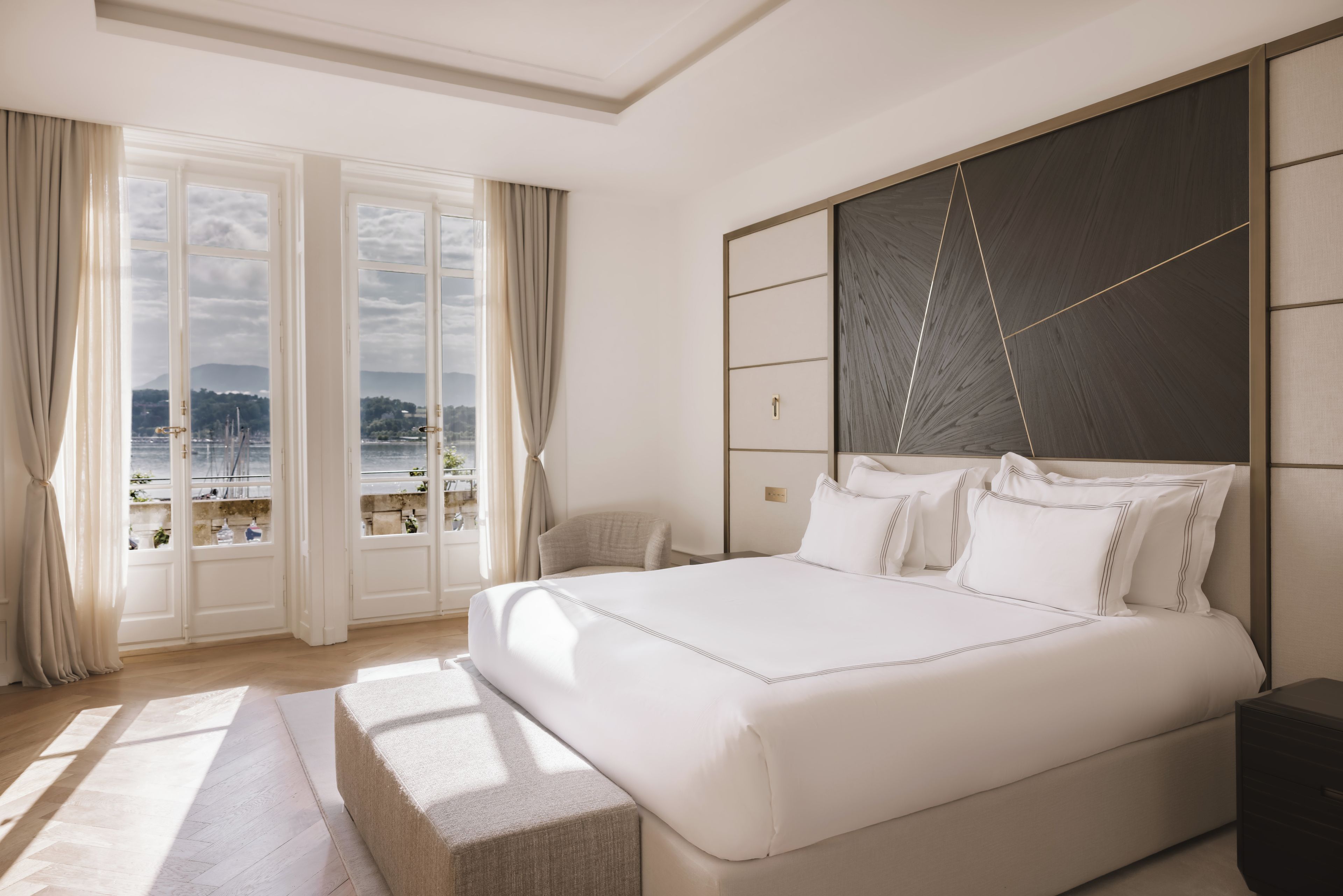 A bedroom with a large bed, a view of the sea through the window, and a modern design.