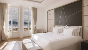 A bedroom with a large bed, a view of the sea through the window, and a modern design.