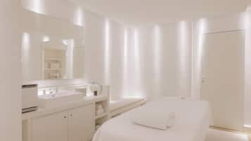 A modern bathroom with a large mirror, a white sink, and a towel on the floor.