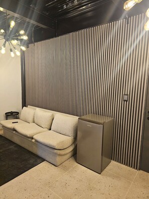 A modern living room with a sofa, a small table, and a compact refrigerator.