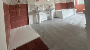 Une salle de bain spacieuse avec une douche, deux lavabos, une baignoire et un grand miroir.