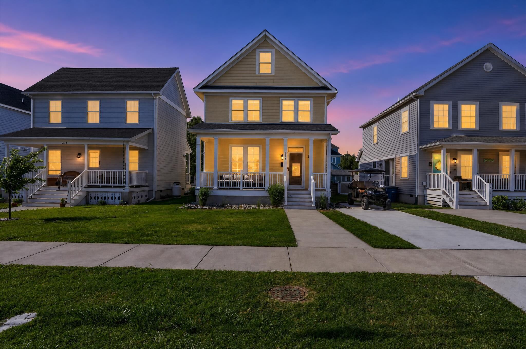 A row of two-story houses with front porches, a driveway, and a well-maintained lawn.