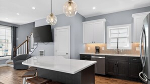 Una cocina moderna con una isla central, armarios oscuros y un refrigerador de acero inoxidable.