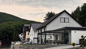 A modern building with a flat roof, large windows, and a covered outdoor area. - A beautiful and cozy vacation bungalow for up to 5 people on the Sonnwaldsteig (Kirn)