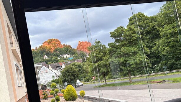 A view from a window with a sofa, a garden, and a distant mountain. - A beautiful and cozy vacation bungalow for up to 5 people on the Sonnwaldsteig (Kirn)