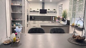 A modern kitchen with white cabinets, a microwave, and a dining area with a table and chairs. - A beautiful and cozy vacation bungalow for up to 5 people on the Sonnwaldsteig (Kirn)