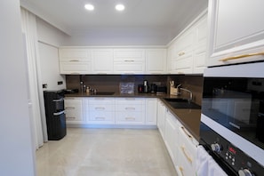 Una cocina moderna con armarios blancos, un refrigerador negro, un horno Samsung y una encimera de acero inoxidable.