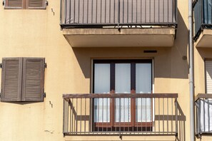 A building with a balcony, a window with shutters, and a door.