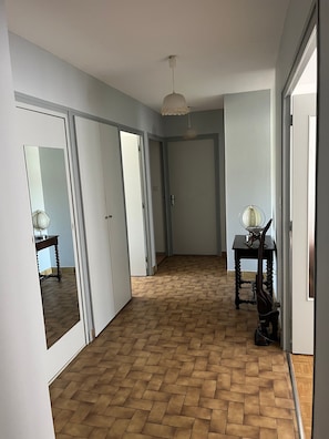 A hallway with a herringbone floor, white walls, and a ceiling light fixture. - T3 Apartment near Alpes Isère Airport with Balcony (Saint-Étienne-de-Saint-Geoirs)