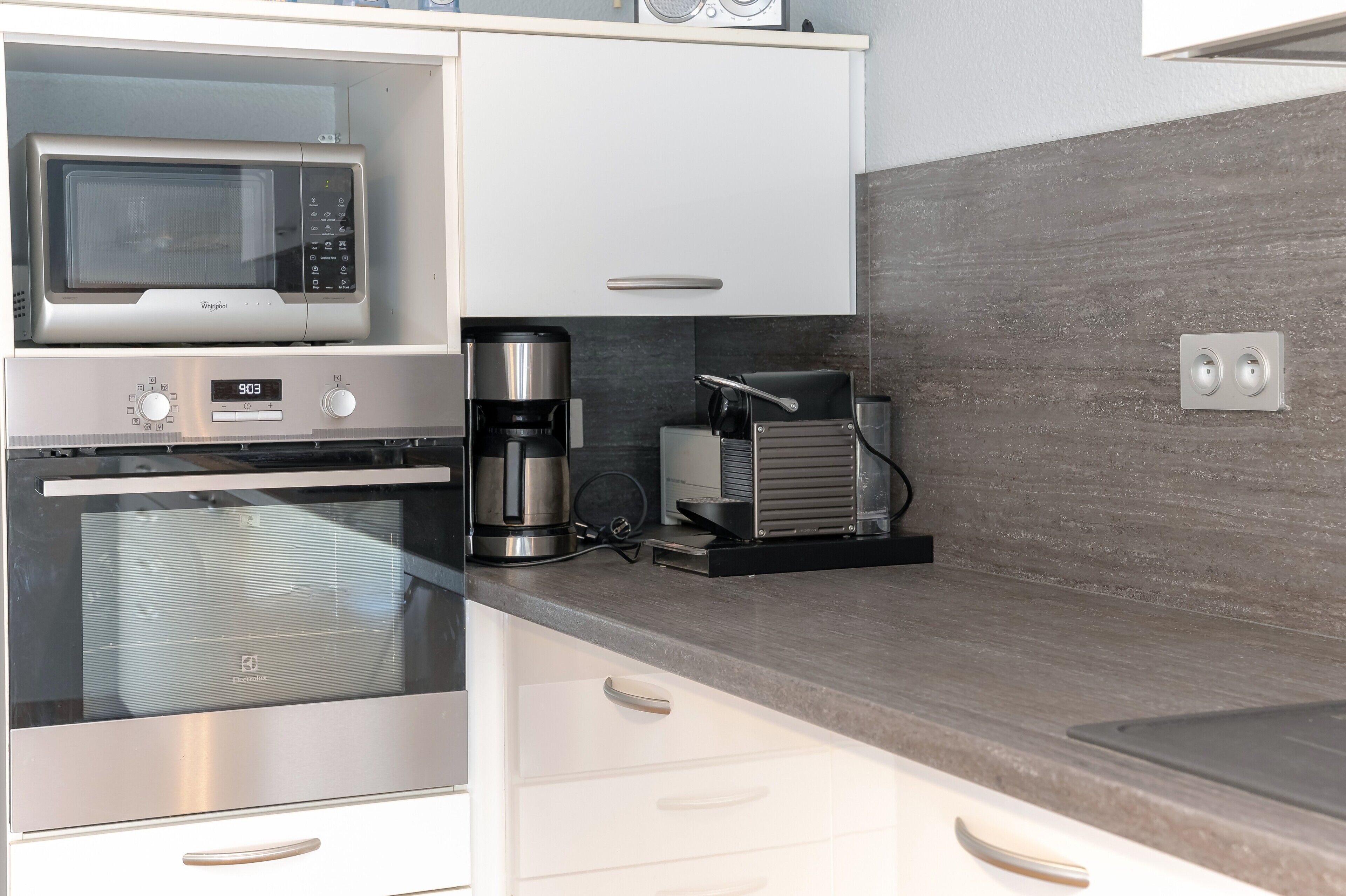 A modern kitchen with a microwave, coffee maker, and toaster.