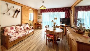 Una sala de estar acogedora con un sofá de madera, una mesa de comedor, sillas, un televisor y una chimenea.