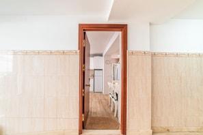 Un couloir avec une porte en bois donnant sur un espace cuisine.