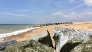 A beach with a rocky shoreline, waves, and a clear sky. - Downs Escape | By My Getaways (Lancing)