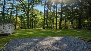 A gravel driveway leading to a grassy area with trees in the background. - Coastal Hideaway Retreat (York)