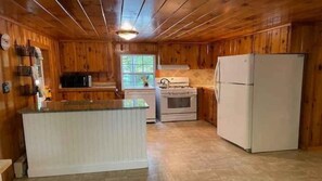 A kitchen with wooden walls, a white refrigerator, a stove, and a microwave. - Coastal Hideaway Retreat (York)
