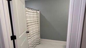A bathroom with a shower curtain, a door, and a tiled floor. - Beautiful Townhouse close to both Short Sands and. (York)