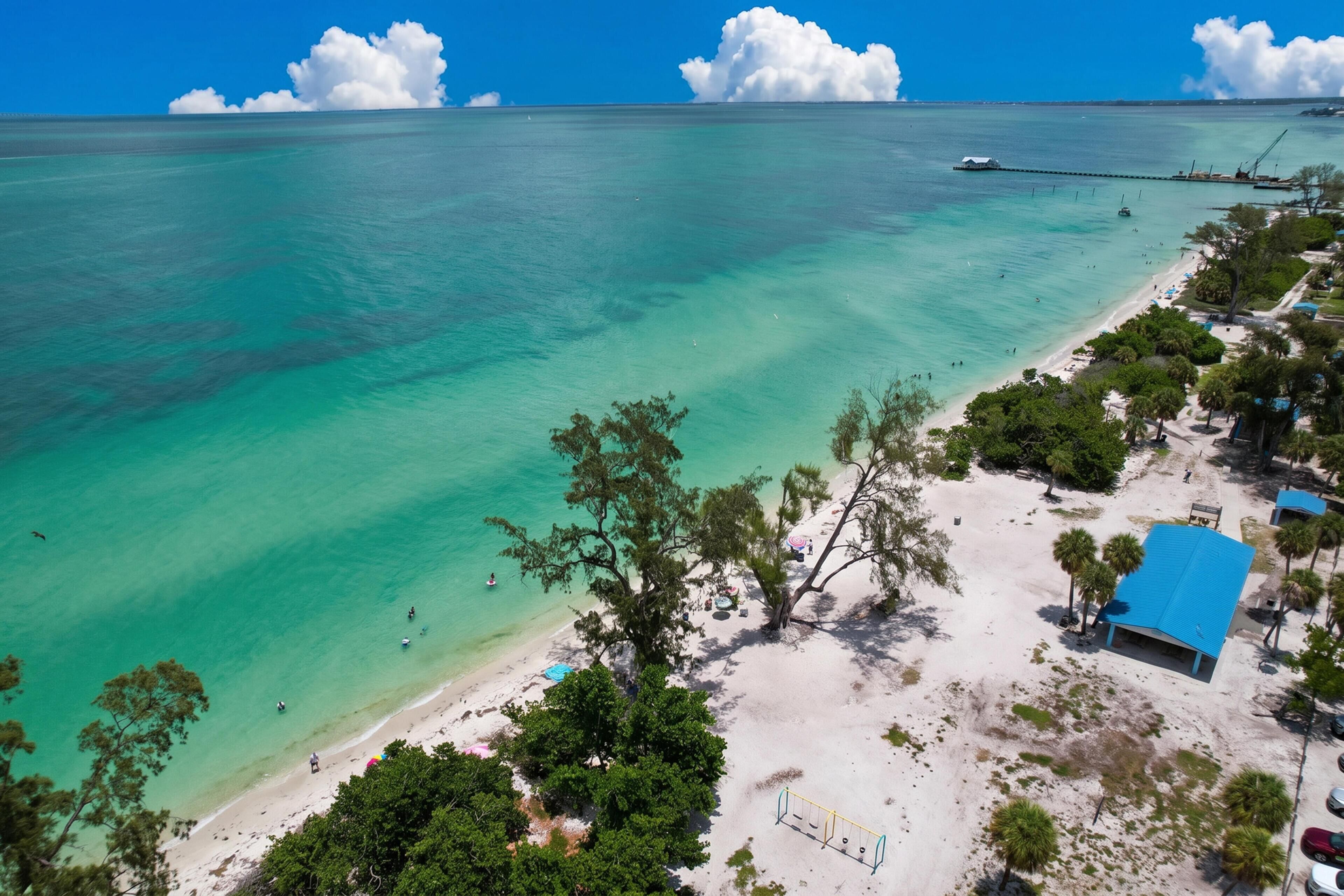 Une plage à l’eau turquoise et limpide, avec un rivage sablonneux et quelques arbres.