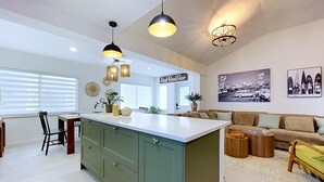 Une cuisine moderne avec un îlot central, un coin repas avec des chaises, un canapé et une table basse.