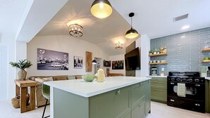 Une cuisine moderne dotée d’un îlot central, de luminaires suspendus et d’une grande cuisinière.