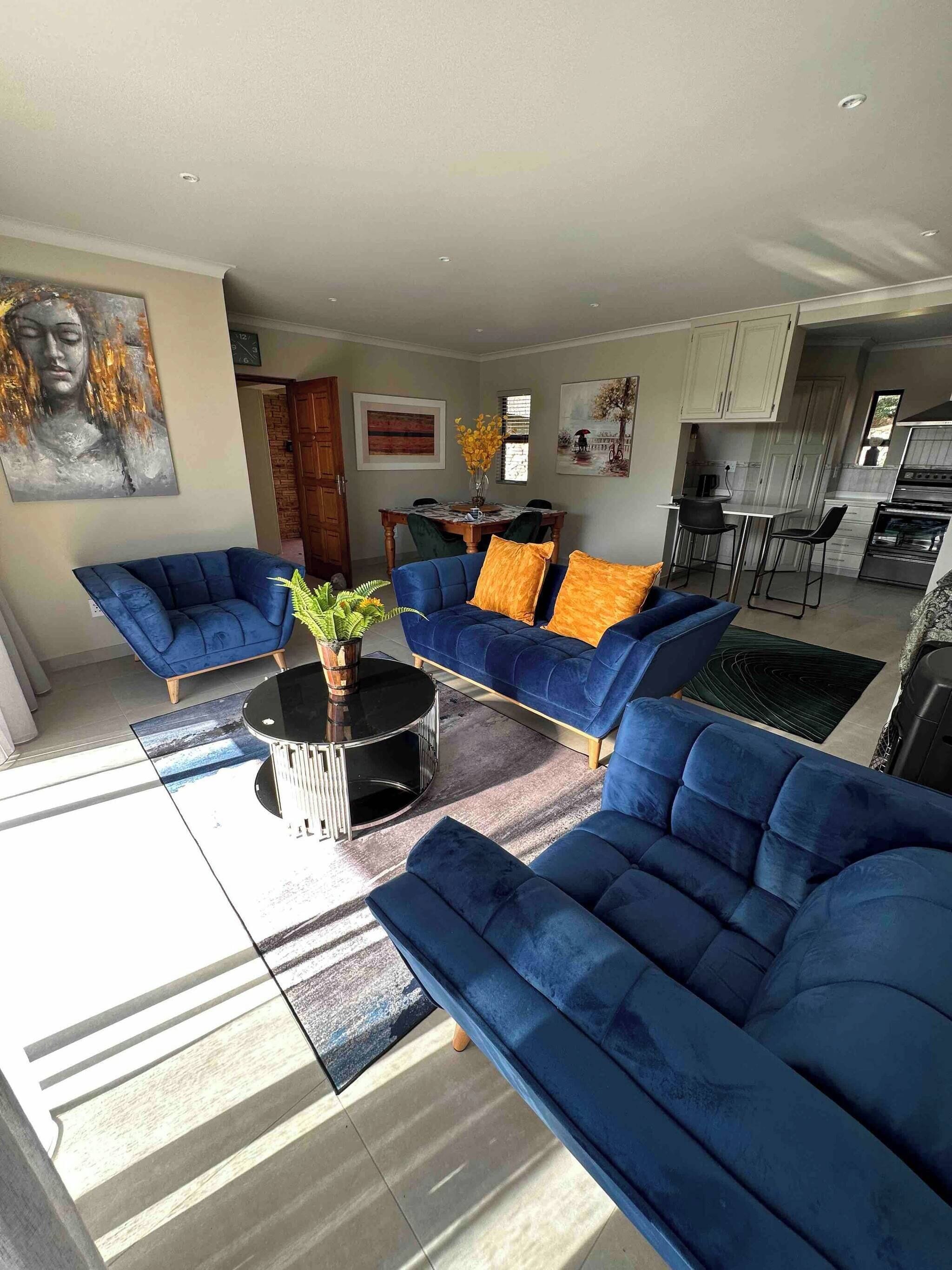 Una sala de estar moderna con sofás azules, una mesa de centro y obras de arte en las paredes.