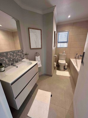 A modern bathroom with a large sink, a toilet, and a bathtub. - Kalistas House Villa (Johannesburg)