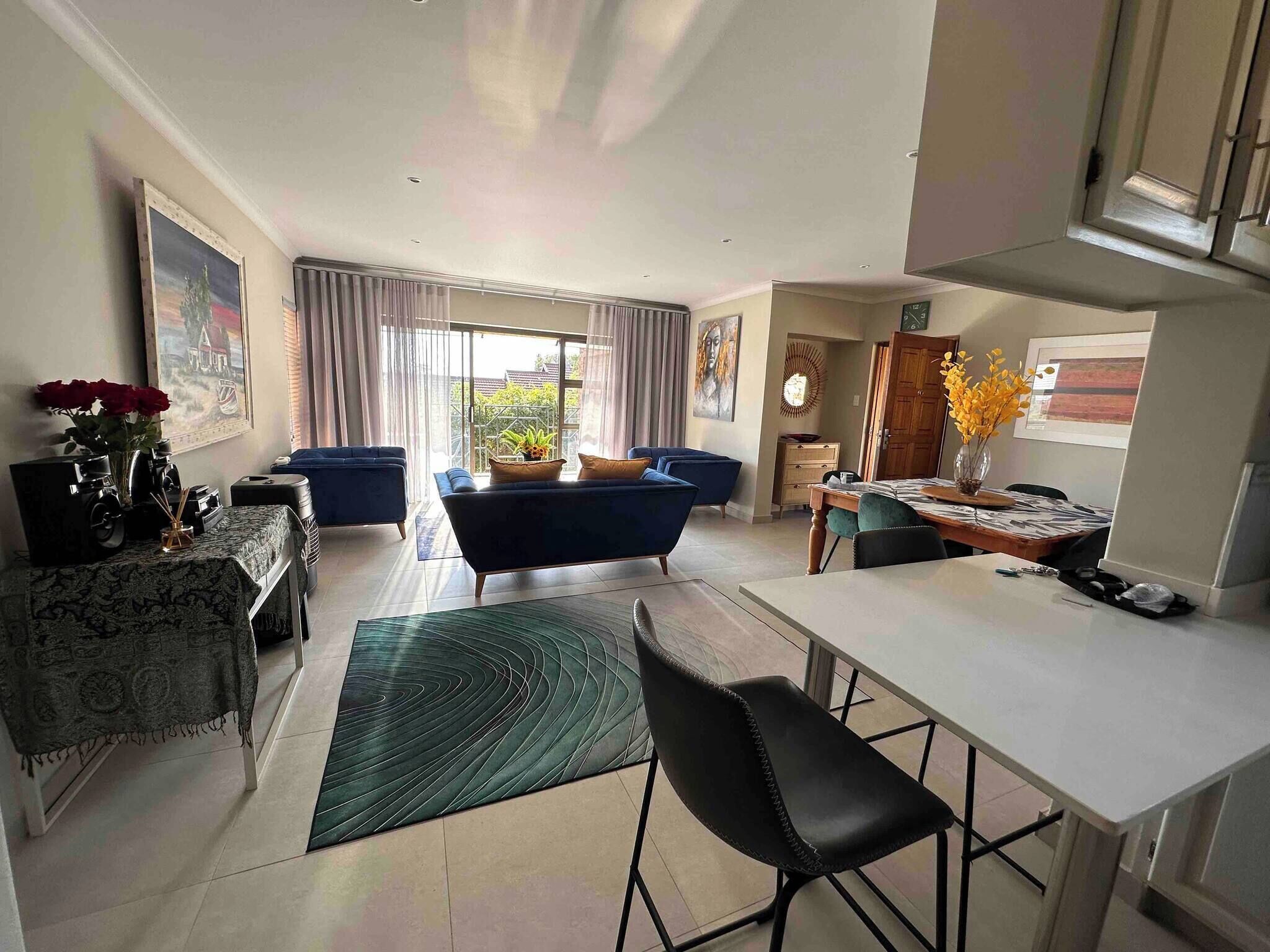 A modern living room with a sofa, a dining table, and a kitchen area.