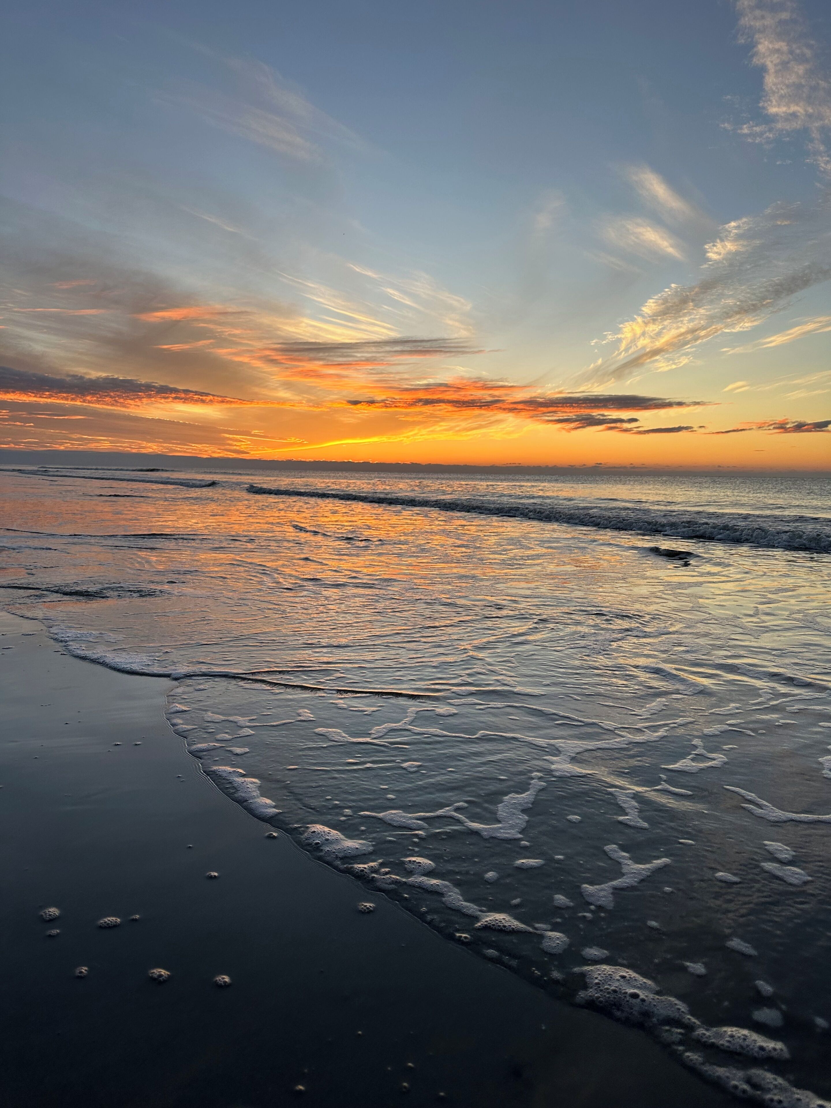 A beach with waves and a sunset.