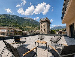 A terrace with outdoor seating, a stone tower, and a mountainous backdrop. - PURA VIDA Tirano - Panoramic Stay (Tirano)