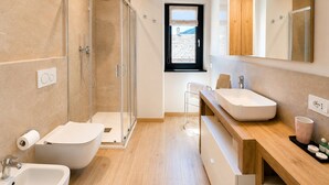A modern bathroom with a glass-enclosed shower, a freestanding bathtub, a sink with a wooden vanity, and a large mirror.