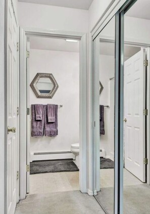 A hallway leading to a bathroom with a toilet, a mirror, and towels on the wall. - A relaxing and inviting retreat in the Reflection Lake area of UMED. (Anchorage)