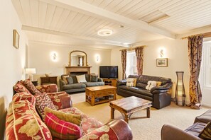 A living room with a fireplace, a television, and two sofas. - Ghyllstead - North East Escapes (Glanton)