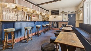 A bar area with stools, a counter with bottles, and a fireplace. - Ghyllstead - North East Escapes (Glanton)