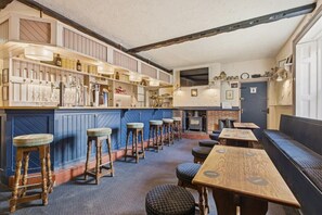 A bar area with stools, a counter with bottles, and a fireplace. - Ghyllstead - North East Escapes (Glanton)
