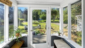 A conservatory with a view of a well-maintained garden. - Once a 1950s Alaska Railroad Section House, this unique home blends modern comfort with vintage soul (Anchorage)