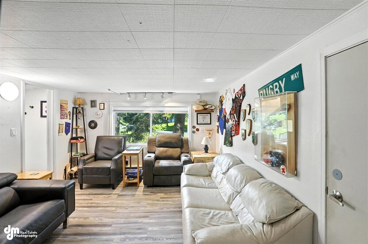 A spacious living room with leather sofas, a fireplace, and a rugby-themed wall sign.