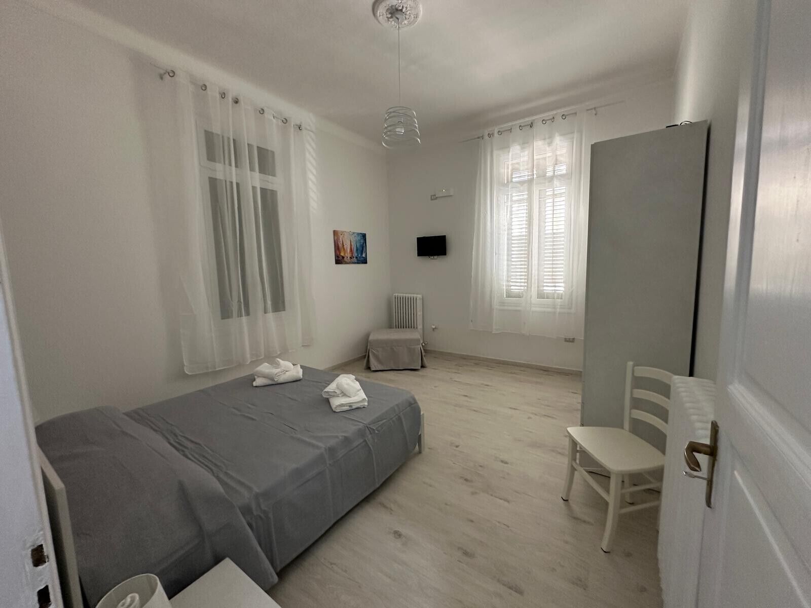 Una camera da letto con un letto, una sedia, un termosifone e una televisione.