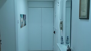A hallway with a white door, a small shelf with toiletries, a framed quote on the wall, and a ceiling light. - Casa Pinuccio Sapri: Bike-Friendly Holiday Home Steps from the Sea (Sapri)