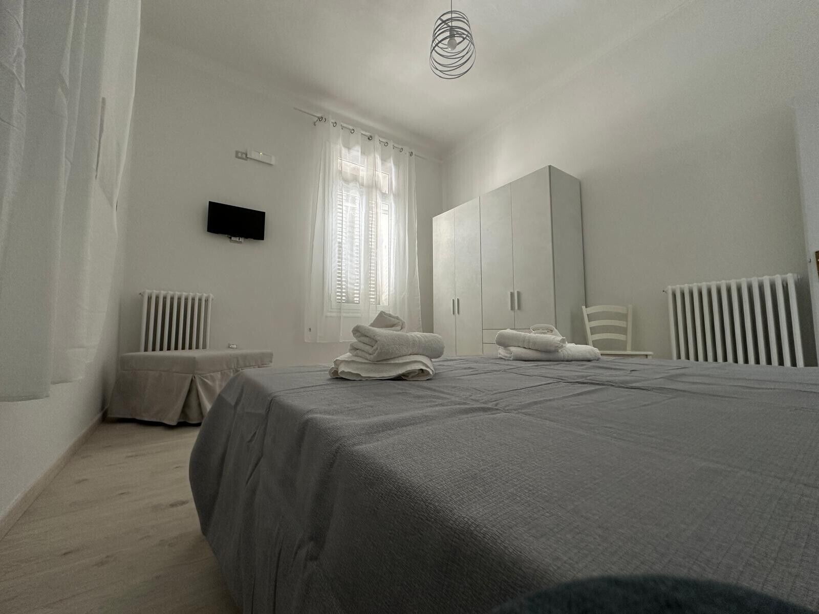 Ein Schlafzimmer mit Bett, Kleiderschrank, Stuhl und Heizkörper.
