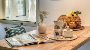 Ein Holztisch mit einer Zeitung, einer Vase mit Trockenblumen, einem Korb voller Zitronen und einer dekorativen Kanne.
