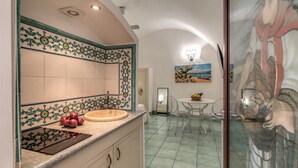 A kitchen with a tiled backsplash, a sink, and a countertop with a fruit bowl. - Lapuritate Via Cariddi - Monolocale piano terra (Gallipoli)
