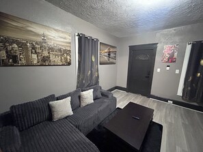 A living room with a sofa, a coffee table, and a cityscape painting on the wall. - Amazing 5-bedroom house in quaint Cleveland perfect for your stay (Cleveland)