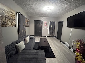 A modern living room with a sofa, a coffee table, a flat-screen TV, and artwork on the walls. - Amazing 5-bedroom house in quaint Cleveland perfect for your stay (Cleveland)