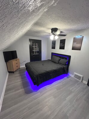 Ein Schlafzimmer mit Bett, Deckenventilator, Tür und Lüftung.