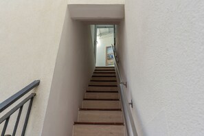 Eine enge Treppe mit Metallgeländer, die zu einer Tür am oberen Ende führt.